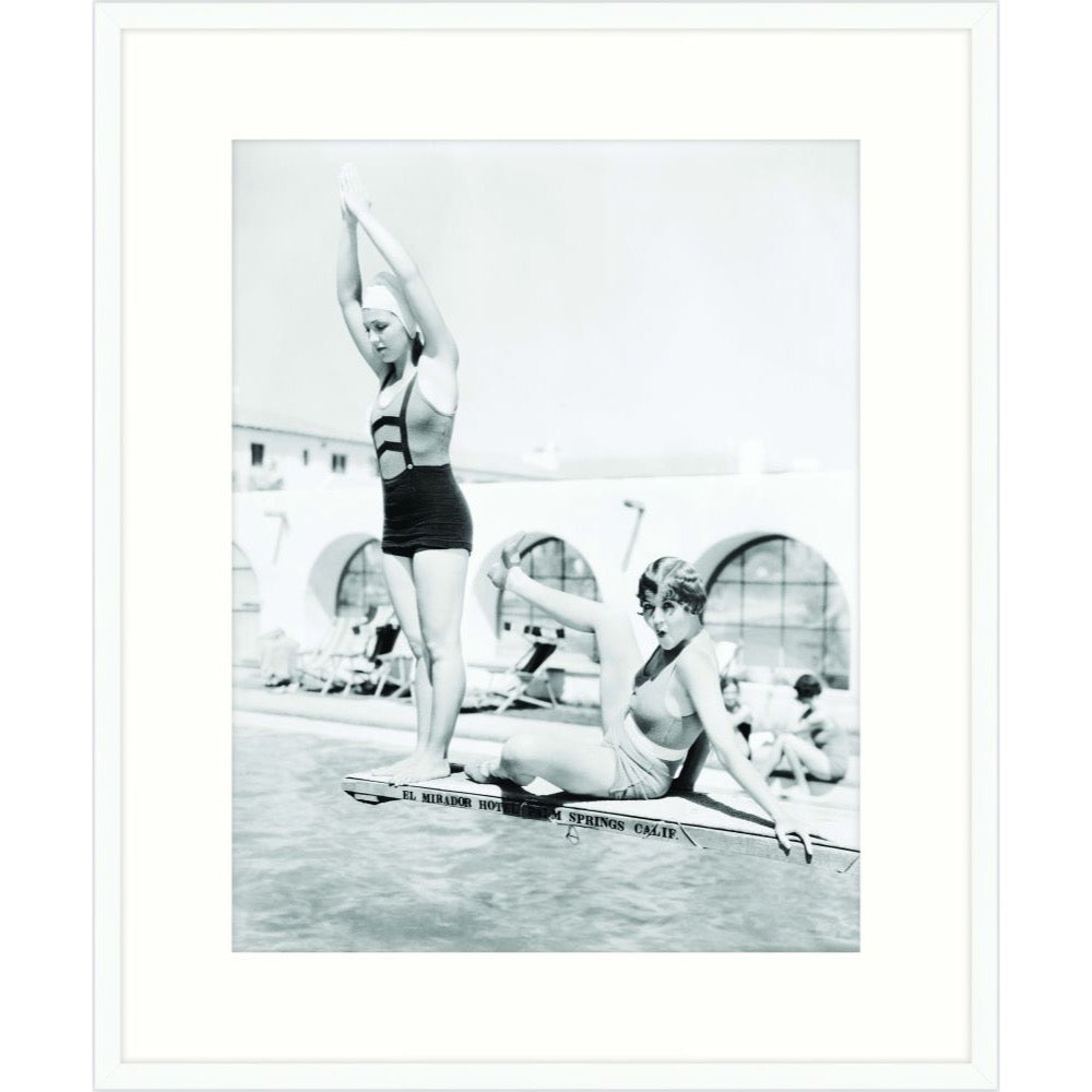 Vintage black and white photograph of two swimmers playing at the edge of a pool