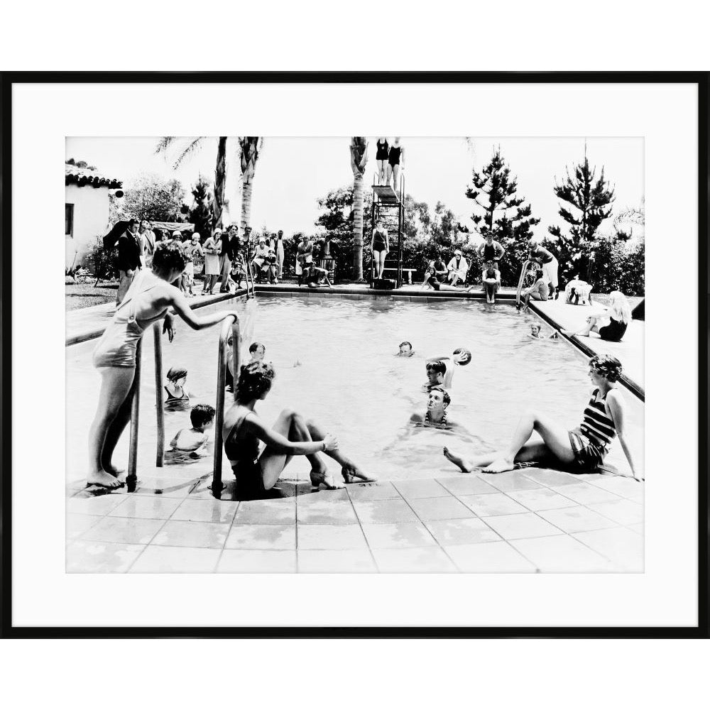Vintage black and white photograph of swimmers lounging around a resort pool