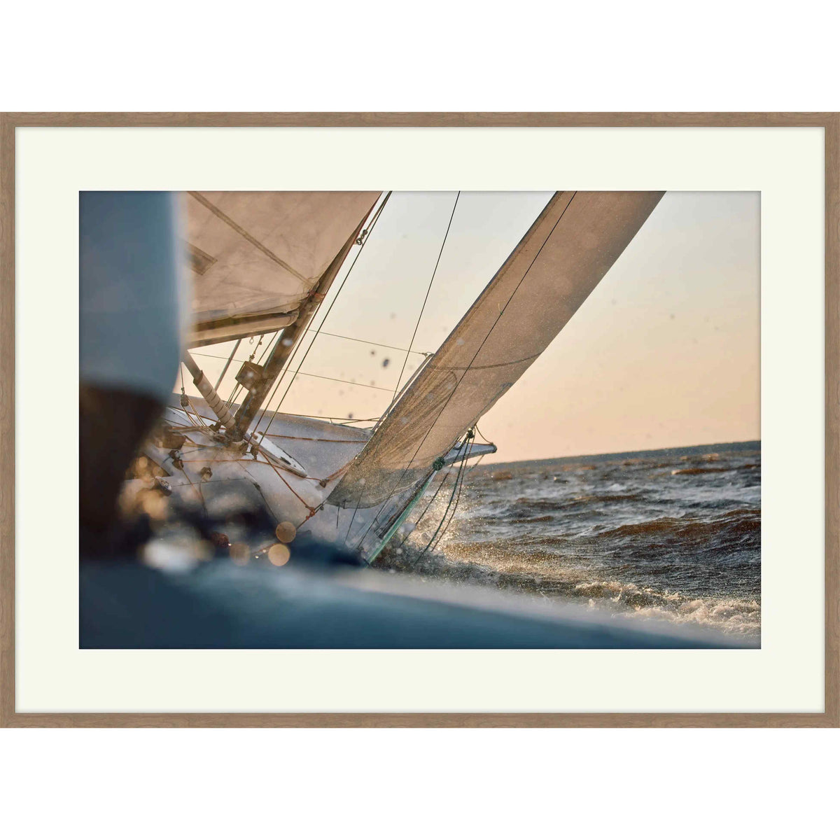 Photograph from the deck of a racing sailboat with billowing sail at golden hour