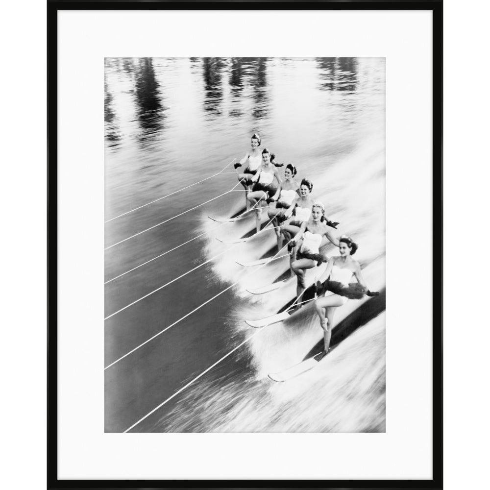Vintage black and white photograph of a line of water skiers in formation