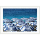 Photograph of navy and white striped beach umbrellas in front of deep blue sea