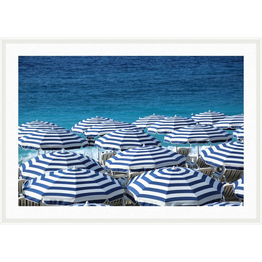 Photograph of navy and white striped beach umbrellas in front of deep blue sea
