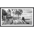 Black and white photograph of a surfboard rental stand with a row of surfboards under palm trees
