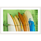 Photograph of cream, gold, and blue surfboards lined up against a lime green wall