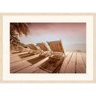 Rose-tinted photograph of wooden lounge chairs on a deck facing the ocean