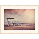 Pink-toned photograph of a lifeguard stand on an empty beach at sunset